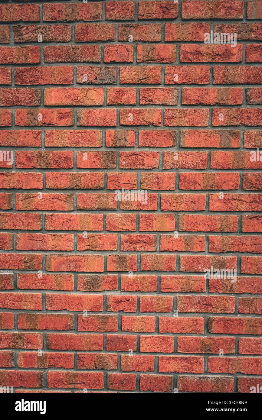 Vollformat rote Ziegelwand mit abwechslungsreichen handgefertigten Ziegeltexturen und dunklen Mörtelverbindungen, die einen warmen architektonischen Hintergrund bilden Stockfoto