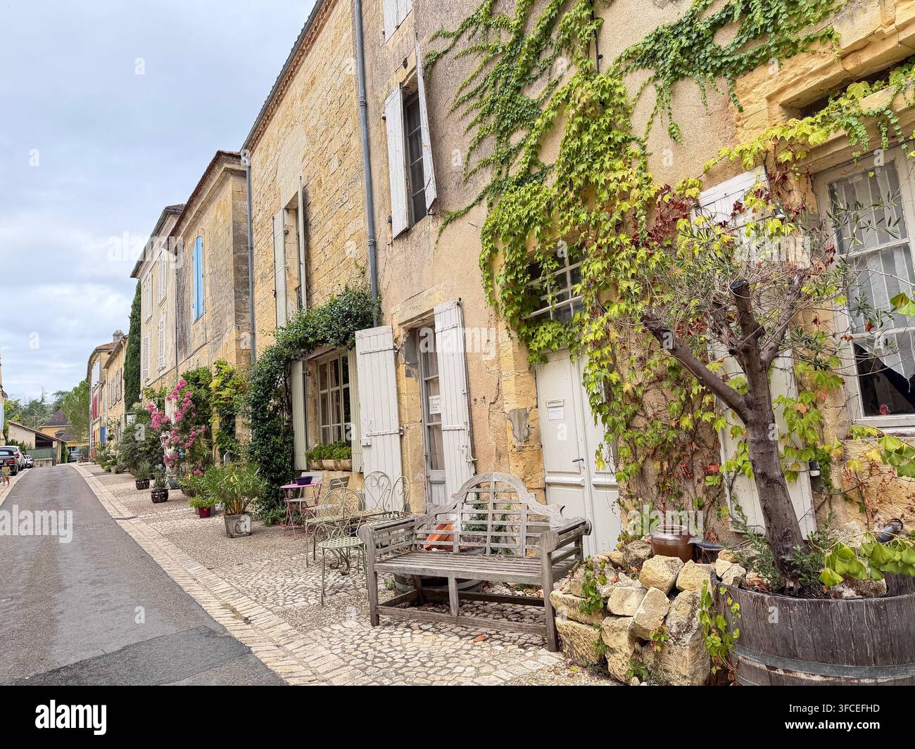 BEAUMONT, FRANKREICH – 20. AUGUST 2026: Historische französische Dorfstraße mit traditionellen Steinhäusern, weißen Fensterläden, Efeu und alten Steinfassaden Stockfoto
