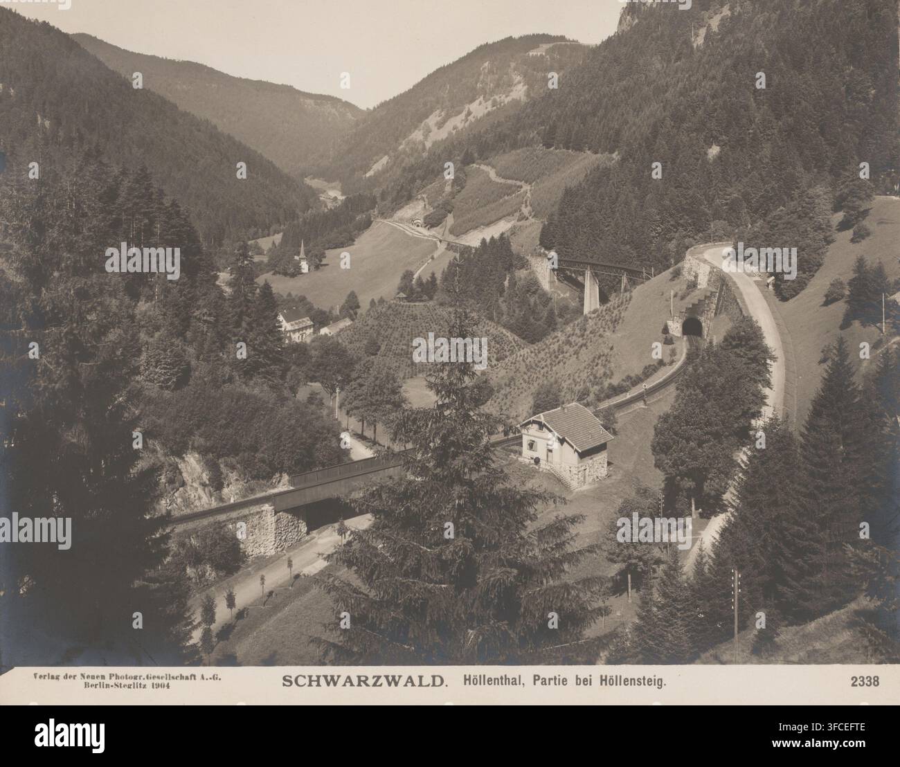 Höllenthal, Schwarzwald, Deutschland, Fotografie, Blick auf ein Tal, Wald, Berge, Eisenbahn und Tunneleingang., Inschrift: 'Verlag der Neuen Photogr.Gesellschaft A.-G., Berlin-Stieglitz 1904', Inschrift: 'SCHARZWALD. Höllenthal, Partie bei Höllensteig.', Nummer: '2338', Verlag: Photographische Gesellschaft Berlin, im Jahr 1904 oder früher, Papier, Gelatinesilberdruck, Entwicklung Gelatinesilberdruck, Höhe 192 mm, Breite 243 mm, Baden-Württemberg, Schwarzwald., Eine sepiafarbene Talszene mit sanften bewaldeten Hügeln und offenen grasbewachsenen Hängen, die eine gewundene Straße und eine Eisenbahn zeigen, die sich kreuzt Stockfoto