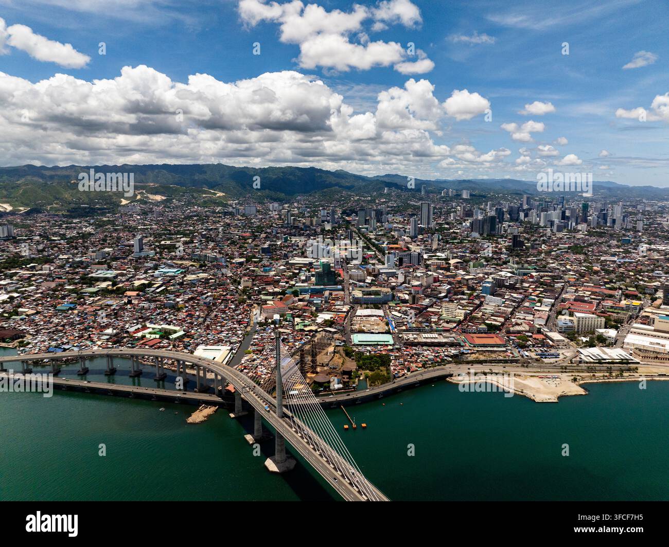 Dichte städtische Stadt mit Wohn- und Geschäftsgebäuden neben einer Hohlkastenbrücke. Cebu, Philippinen. CCLEX. Stockfoto
