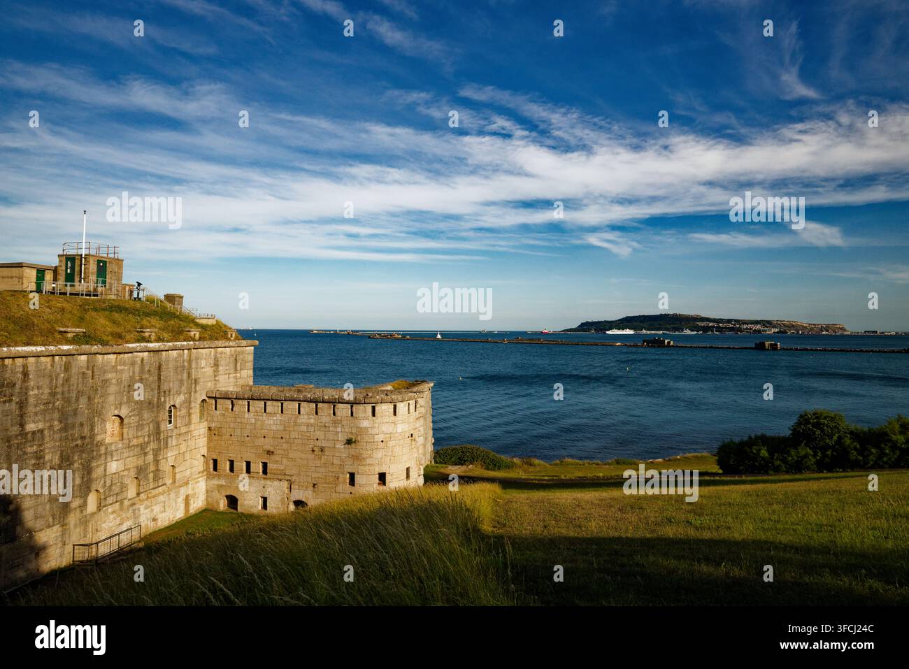 Ein Bastion und Beobachtungsposten überblickt ein ruhiges blaues Meer von einem grasbewachsenen Küstenpark in Richtung der Isle of Portland, Nothe Fort, Weymouth, Dorset, England. Stockfoto