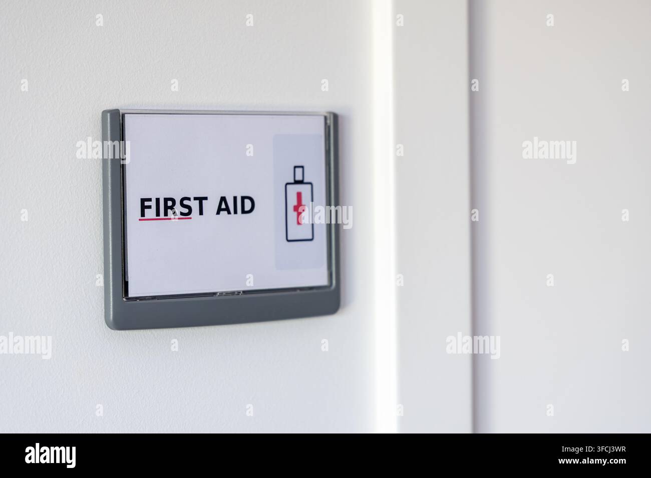 Ein klares und sichtbares Erste-Hilfe-Schild mit einem medizinischen Kreuzsymbol ist an einer Wand angebracht, das den Standort von Notfallmedizinerausrüstung kennzeichnet Stockfoto