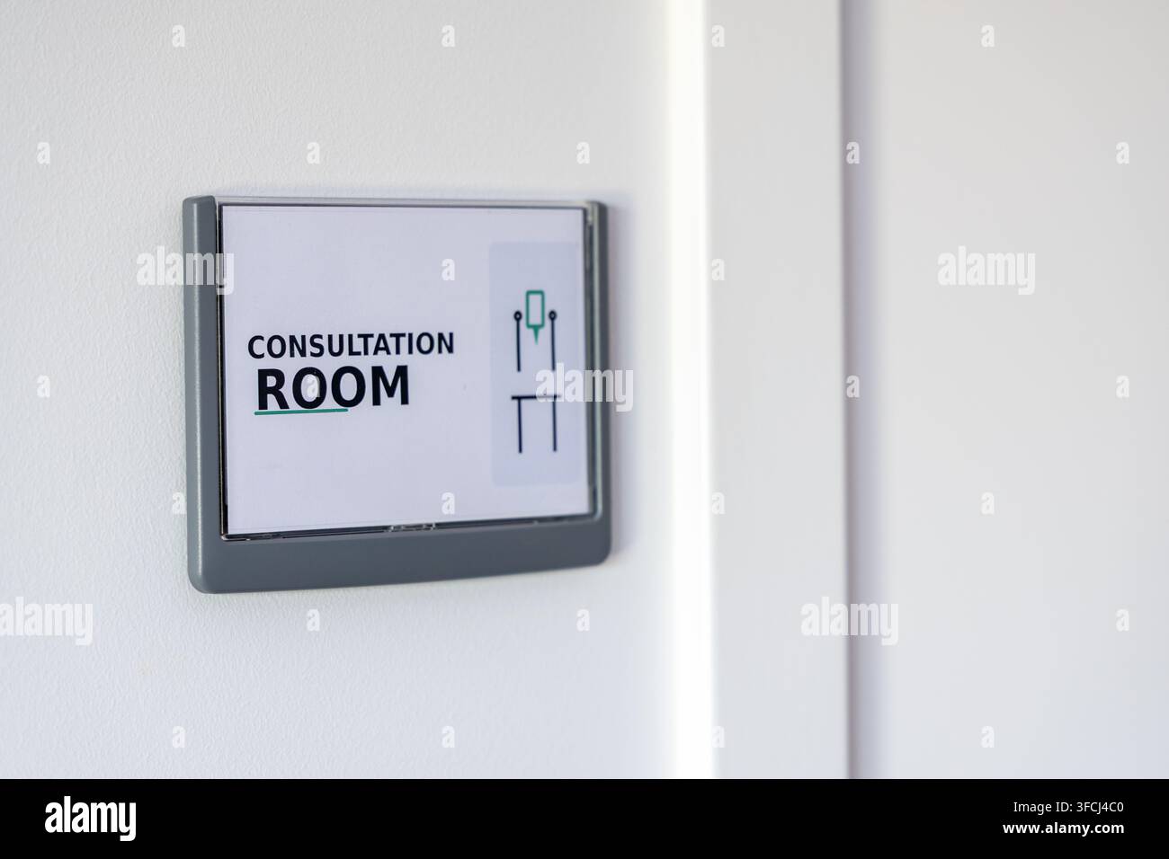 Ein klares Schild, das einen Beratungsraum anzeigt, ist an einer strukturierten weißen Wand neben einer Tür angebracht Stockfoto