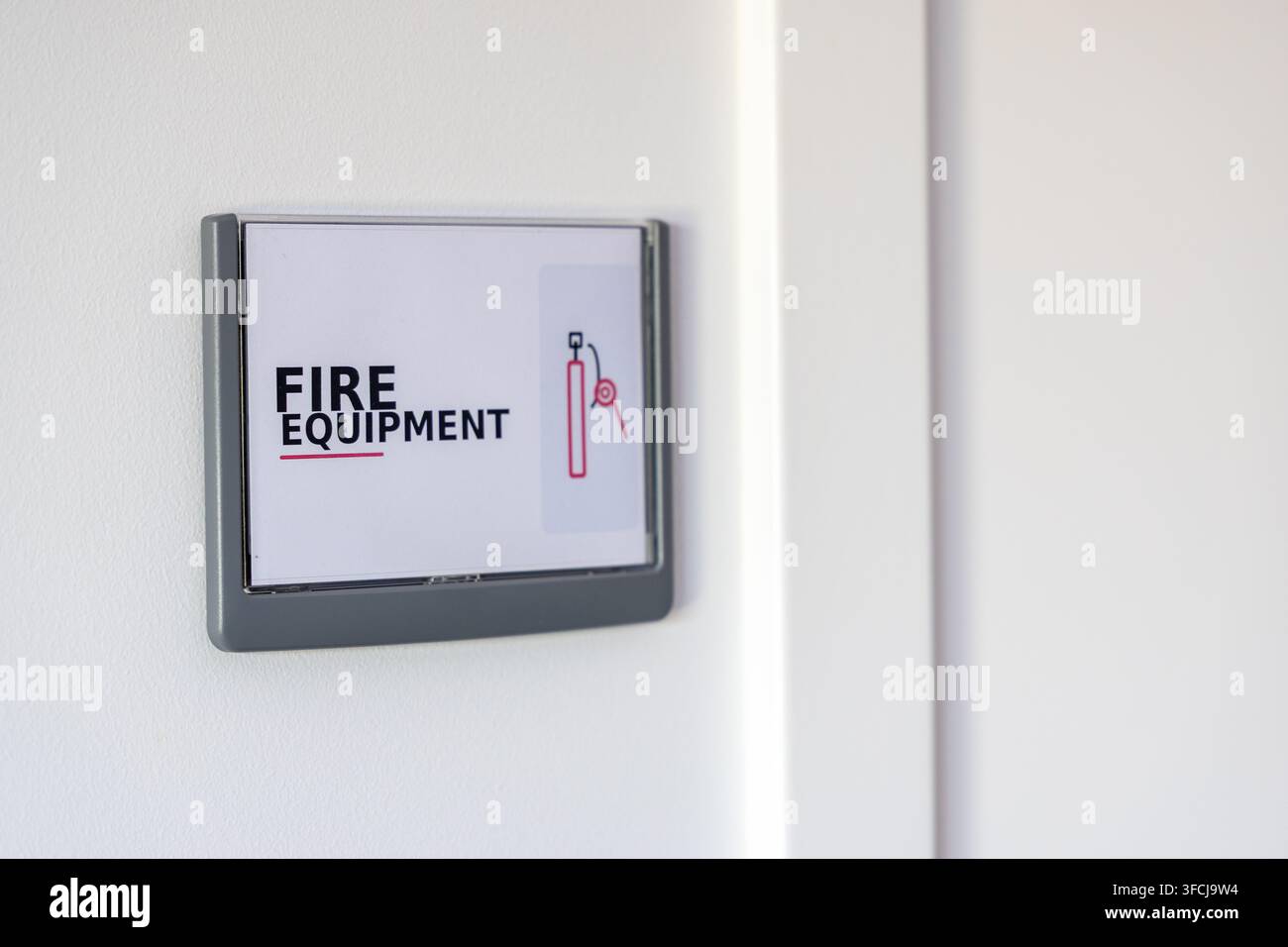 Ein klares Schild mit den Worten FEUERGERÄTE und einem Symbol eines Feuerlöschers ist an einer weißen Wand angebracht Stockfoto