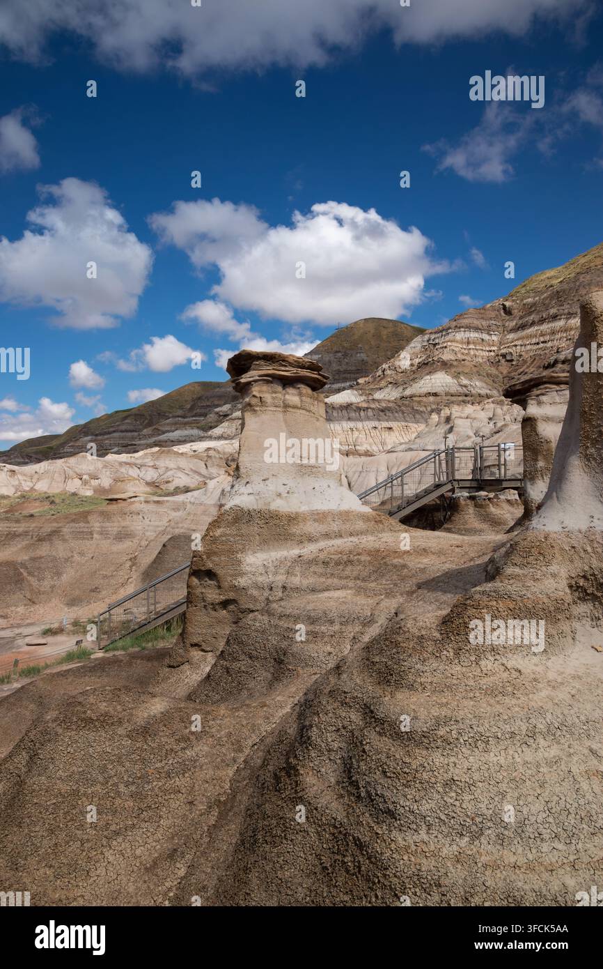 Blick auf die Hoodoos-Felsformationen mit Sandsteinschichten, Holzsteg und blauem Himmel in Drumheller, Alberta, Kanada. Stockfoto