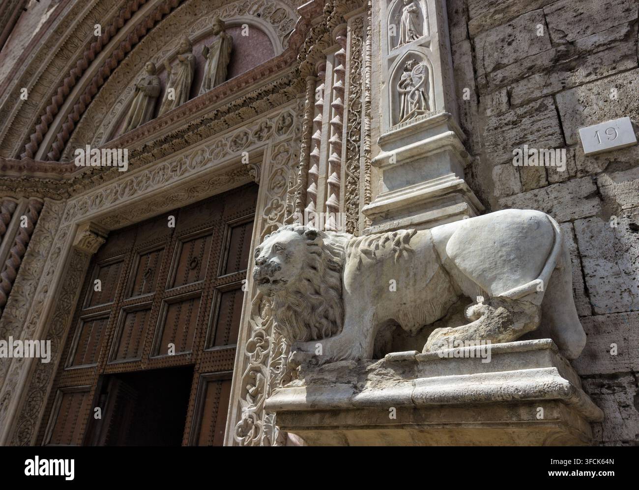 Detail des Haupteingangsportals des Palazzo dei Priori in Perugia, Umbrien, Italien. Gotisches Portal verziert mit einer Marmorlöwenstatue Stockfoto