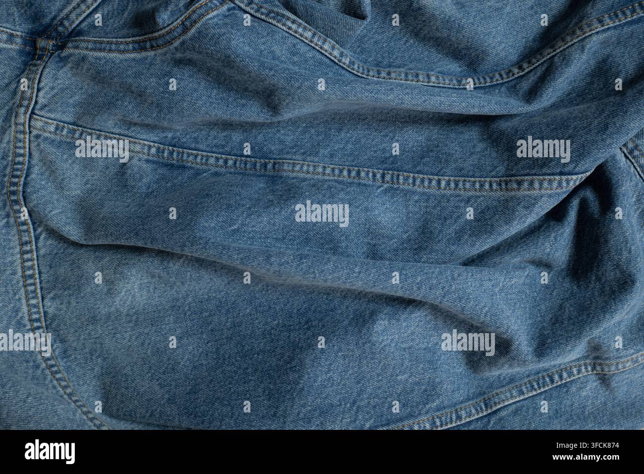 Blauer zerknitterter Denimstoff, der seine Textur und genähte Nähte zeigt Stockfoto