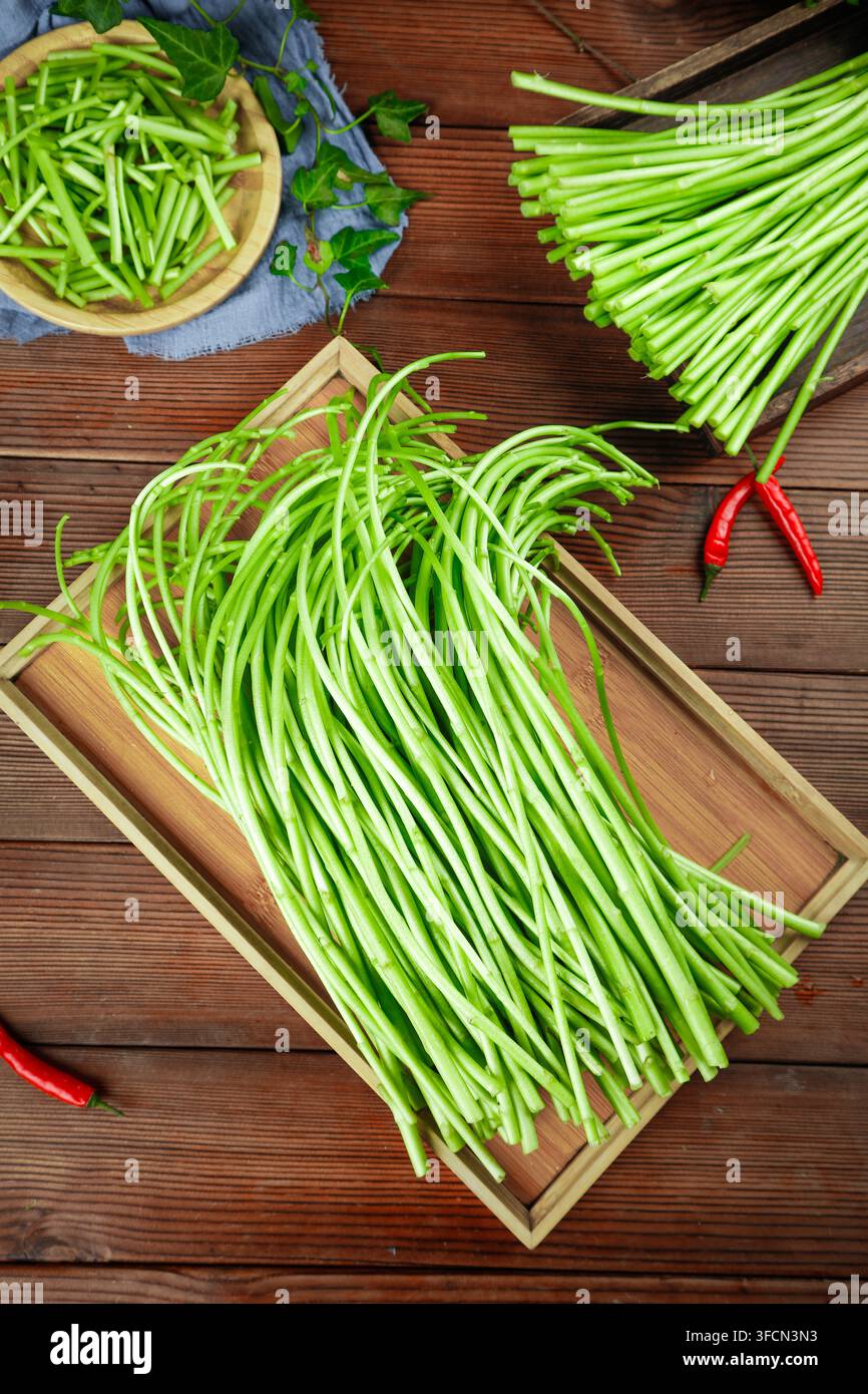 Frische Knoblauchschoten auf einem Holztablett über einem rustikalen Tisch angeordnet. Stockfoto