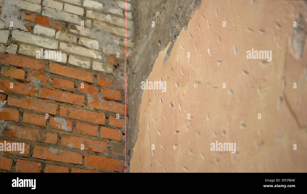 Reparatur, den Laserniveau an der Wand freilegen. Die Wände mit einem Laserniveau ausrichten. Installation von neuen Fliesen an der Wand mit einem Laserniveau Stockfoto