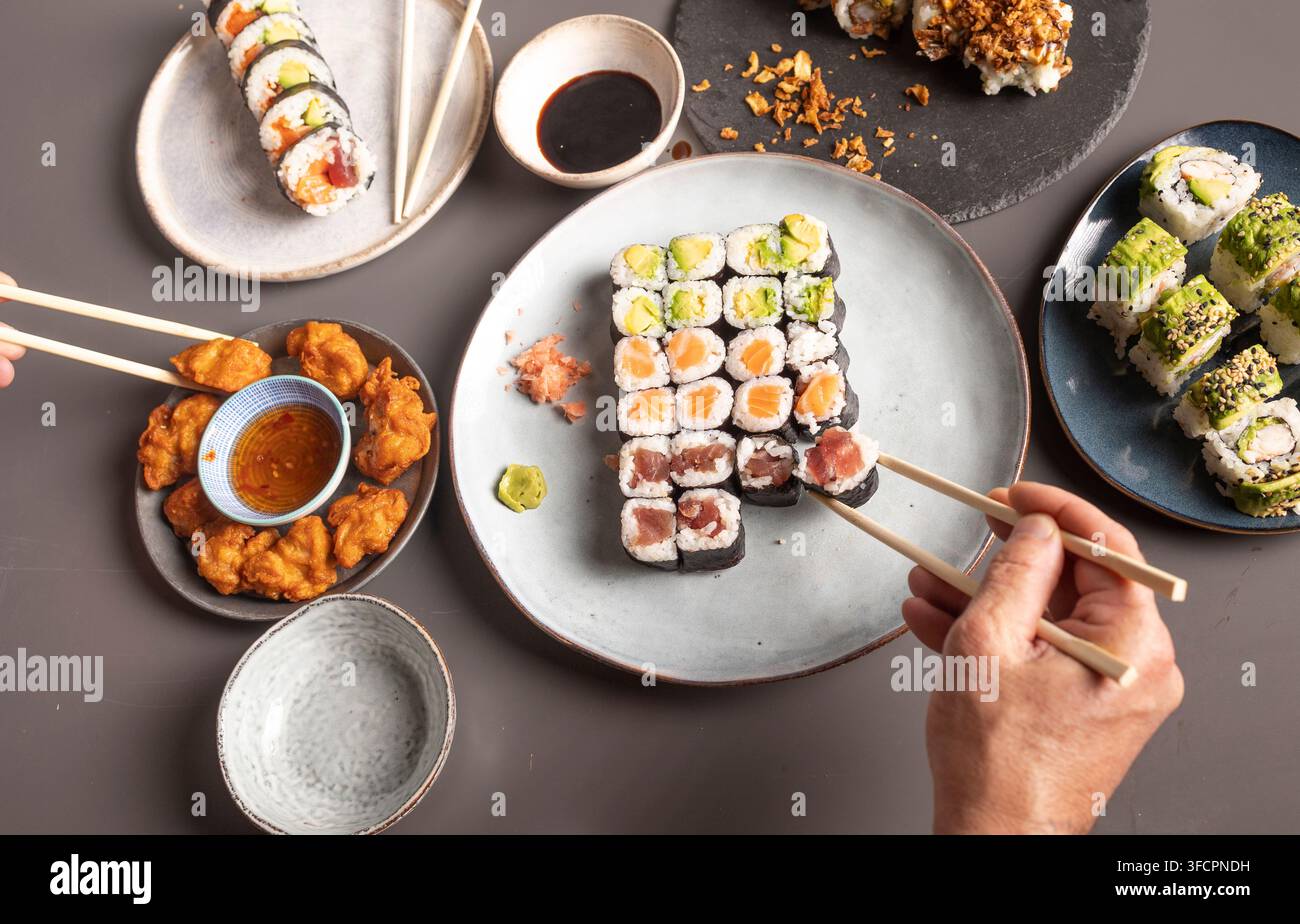 Menschen, die Sushi und japanisches gebratenes Hühnchen zum Abendessen genießen Stockfoto