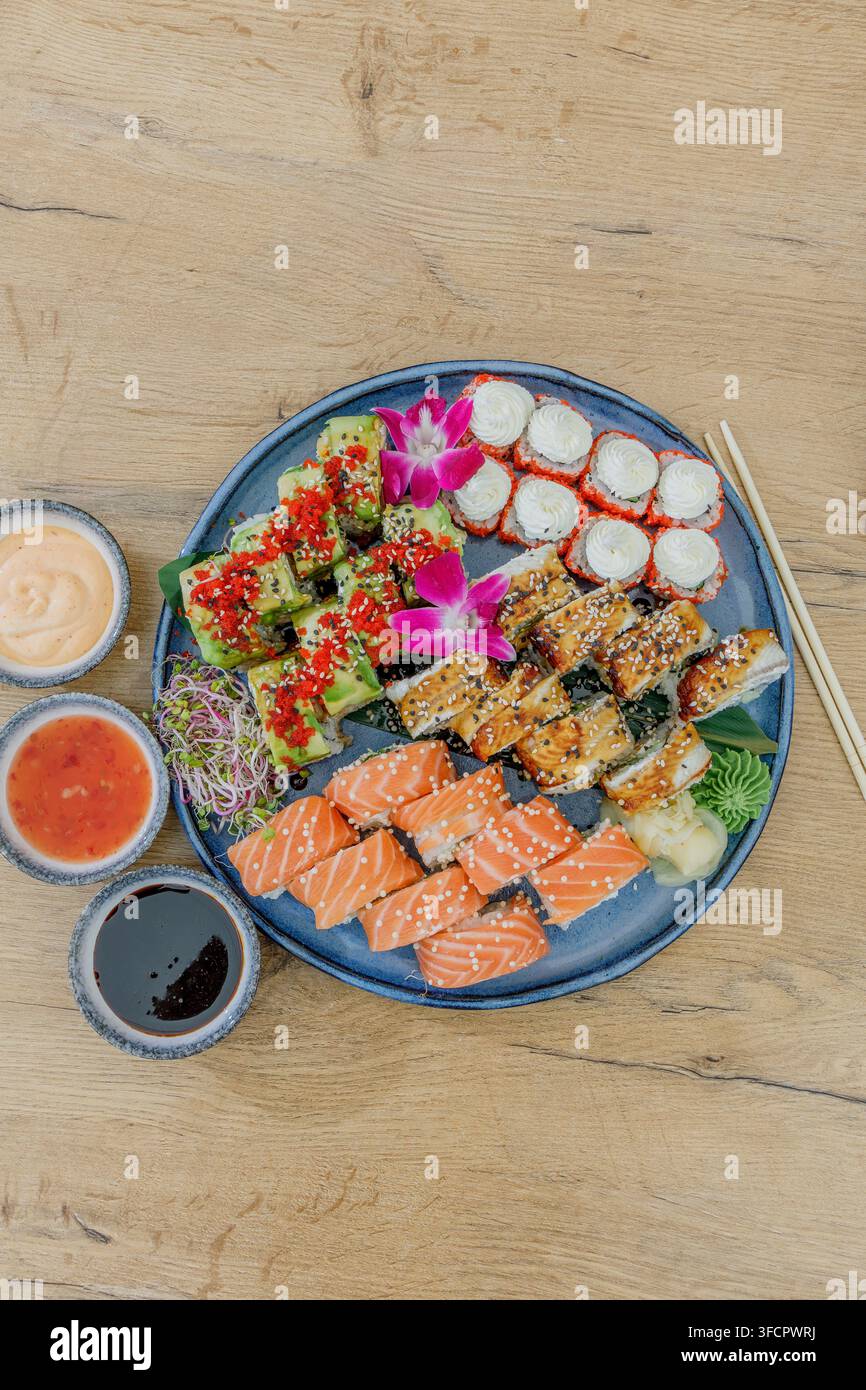 Ein großes gemischtes Sushi-Platte auf einem Holztisch mit Saucen Stockfoto