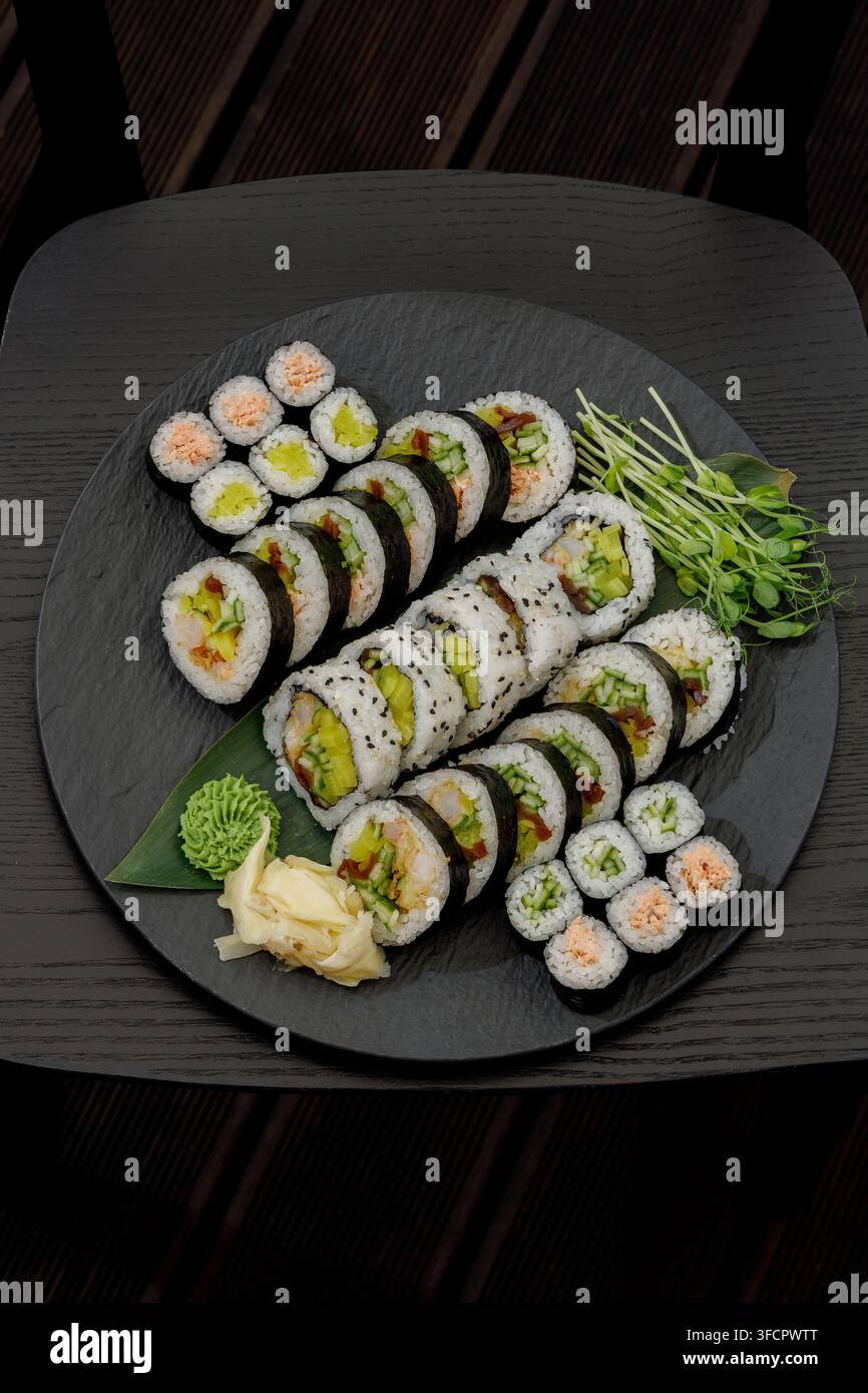 Eine köstliche Auswahl an frischen Sushi-Rollen auf einem dunklen Teller Stockfoto