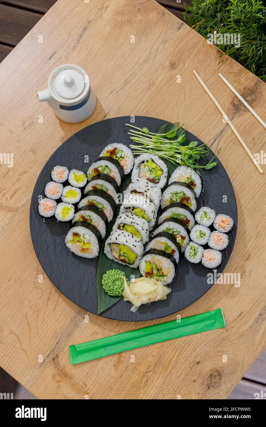 Ein großes Tablett mit verschiedenen Sushi-Rollen auf einem Holztisch Stockfoto