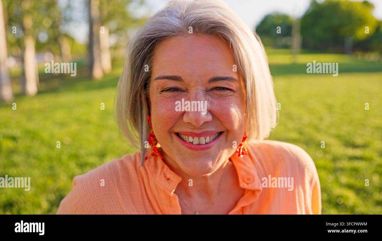 Seniorin lächelt und genießt einen fröhlichen Moment im Freien im Park Stockfoto