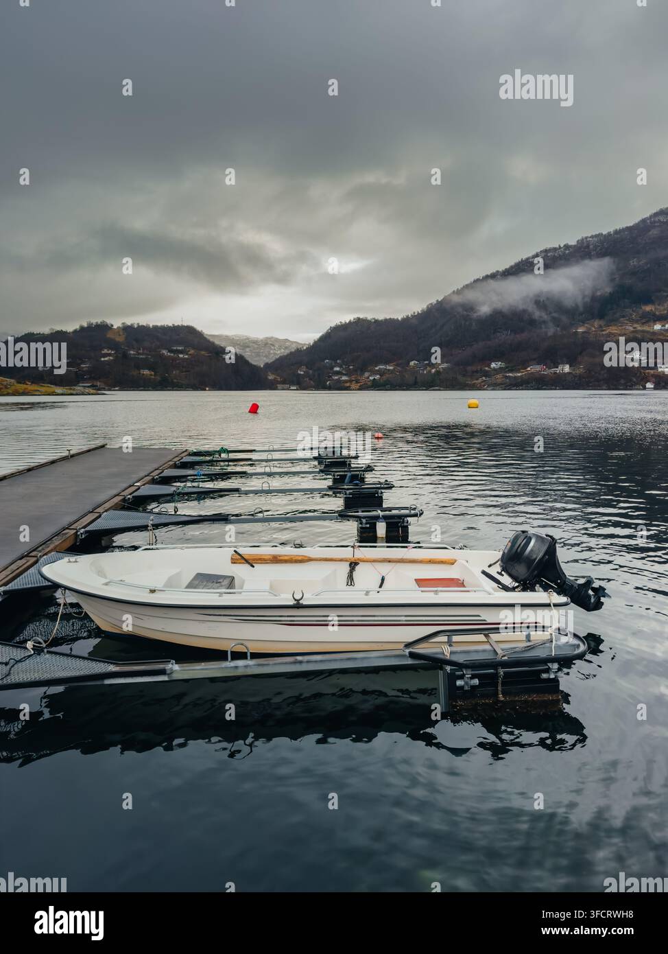 Ein weißes offenes Motorboot mit Außenbordmotor ist an einem modernen schwimmenden Piersystem befestigt Stockfoto