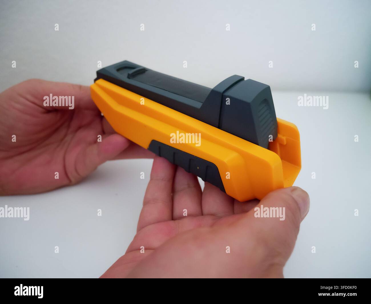 Nahaufnahme einer Demonstration von Händen, die eine orange-schwarze Zigarettenrolle mit Tabak verwenden, um handgedrehte Zigaretten herzustellen. Zeigt detaillierte DIY-Rauchausrüstung Stockfoto