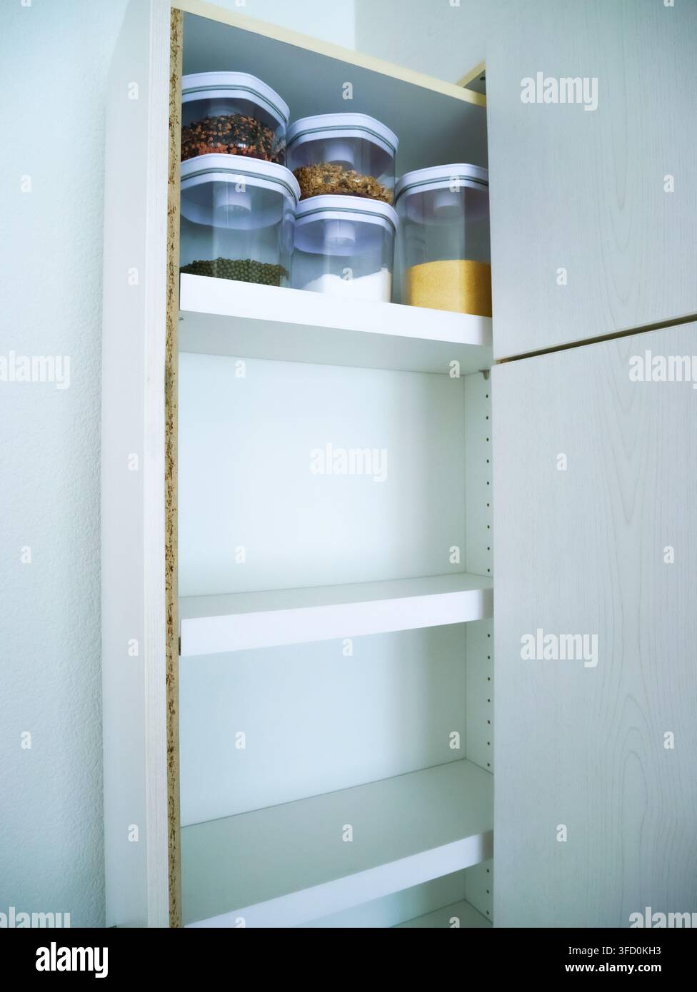 Nahaufnahme von Küchenschrankschüben gefüllt mit klaren Glasvorratsbehältern und organisierten Gläsern. Zeigt eine effektive Lösung für die Vorratsschränke Stockfoto