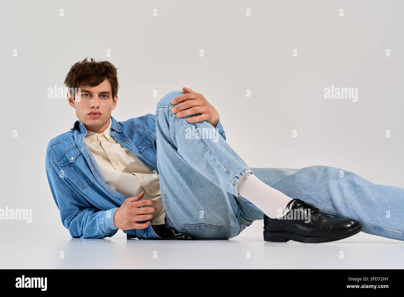 Modisch im Studio posiert, zeigt ein junger Mann trendigen Streetstyle in Jeans Stockfoto
