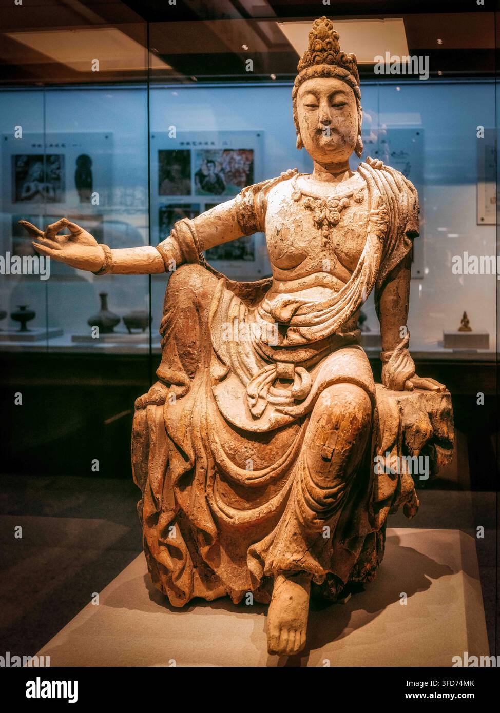 Zwei bemalte hölzerne Guanyin-Statuen, die in der Yangguan-Site-Ausstellungshalle ausgestellt sind. Eine steht auf einem Lotus-Sockel, während die andere in entspannter Pose sitzt Stockfoto