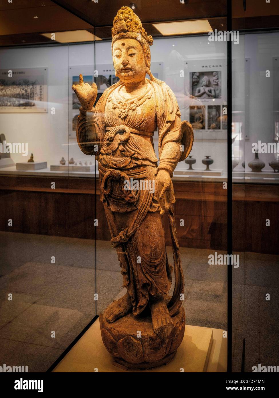 Zwei bemalte hölzerne Guanyin-Statuen, die in der Yangguan-Site-Ausstellungshalle ausgestellt sind. Eine steht auf einem Lotus-Sockel, während die andere in entspannter Pose sitzt Stockfoto