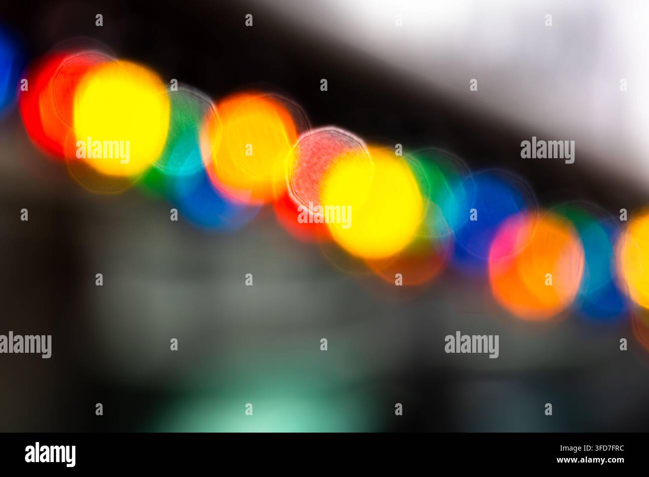 Abstrakte verschwommene Fadenlichter in Rot, Gelb, Grün, Blau und Orange erzeugen farbenfrohe Bokeh-Kreise vor einem dunklen Hintergrund. Stockfoto