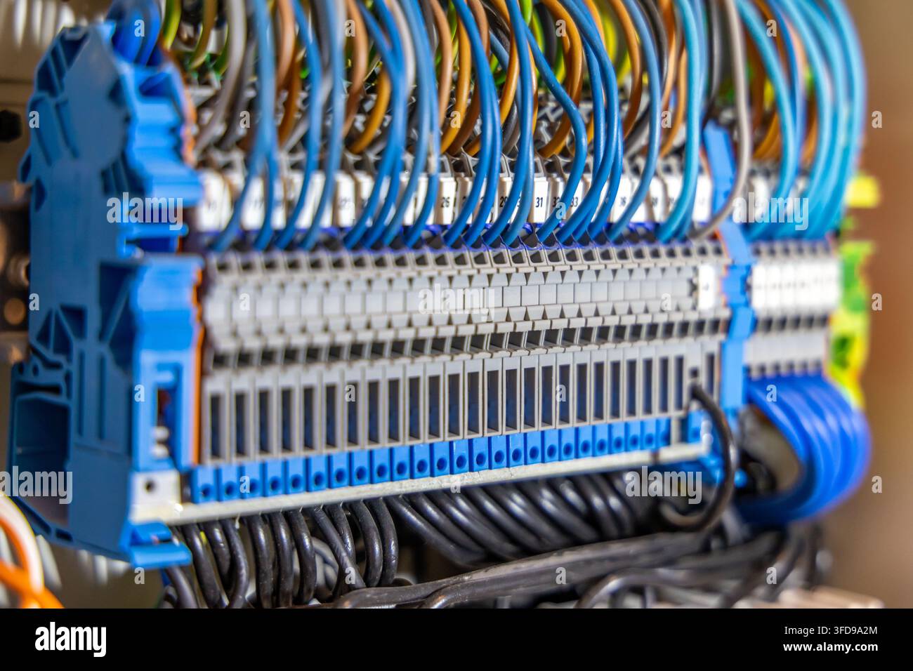 Eine detaillierte Perspektive eines dicht verkabelten elektrischen Schalters mit mehreren Reihen von Klemmblöcken und farbig isolierten Kabeln Stockfoto