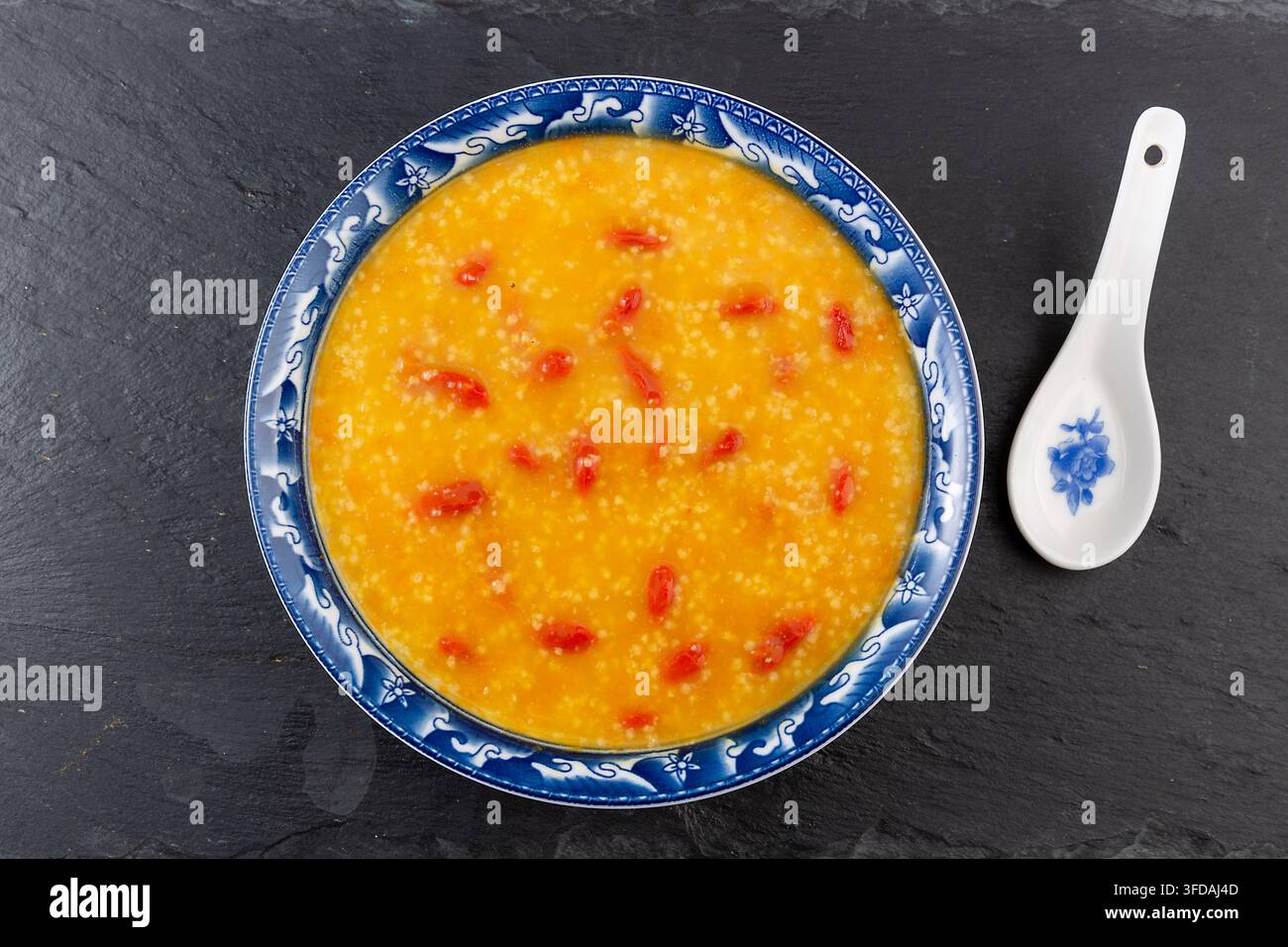 Goldener Hirse-Kürbisbrei garniert mit getrockneten Goji-Beeren Stockfoto