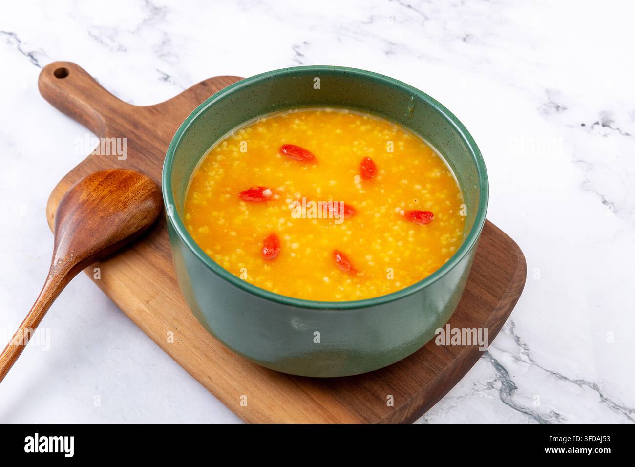 Goldener Hirse-Kürbisbrei garniert mit getrockneten Goji-Beeren Stockfoto