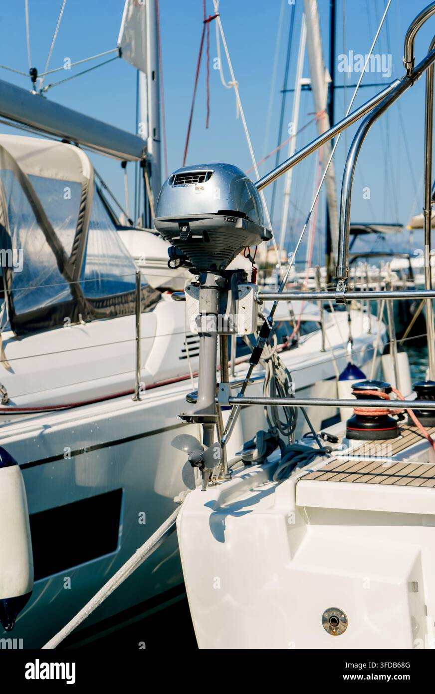 Außenbordmotor auf dem Heck eines Segelboots in einer modernen Marina montiert. Konzept von Wassertransport, Navigation, Wartung und Reisen Stockfoto