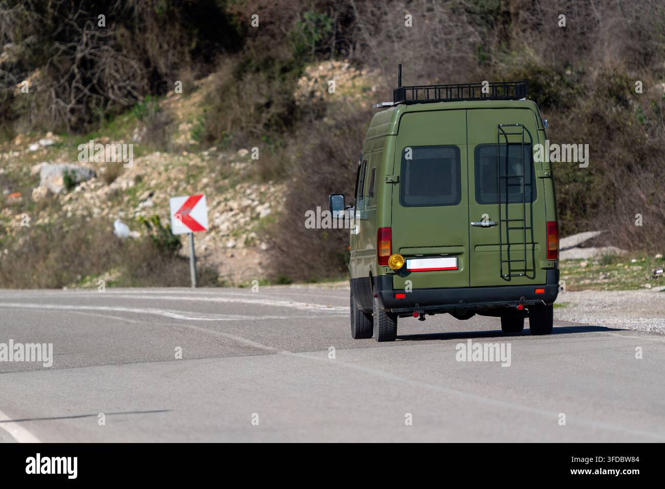 Rückansicht eines olivgrünen umgebauten Wohnwagens, der während einer Roadtrip auf einer Landstraße fährt Stockfoto