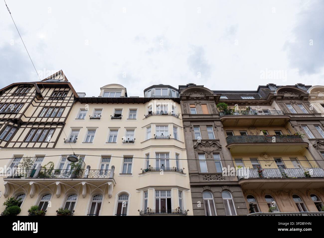 WIEN, ÖSTERREICH, 25. August 2026: Niederwinkelaufnahme historischer europäischer Wohnhäuser mit verzierten Fassaden und Balkonen unter einer bewölkten Himmel. Stockfoto