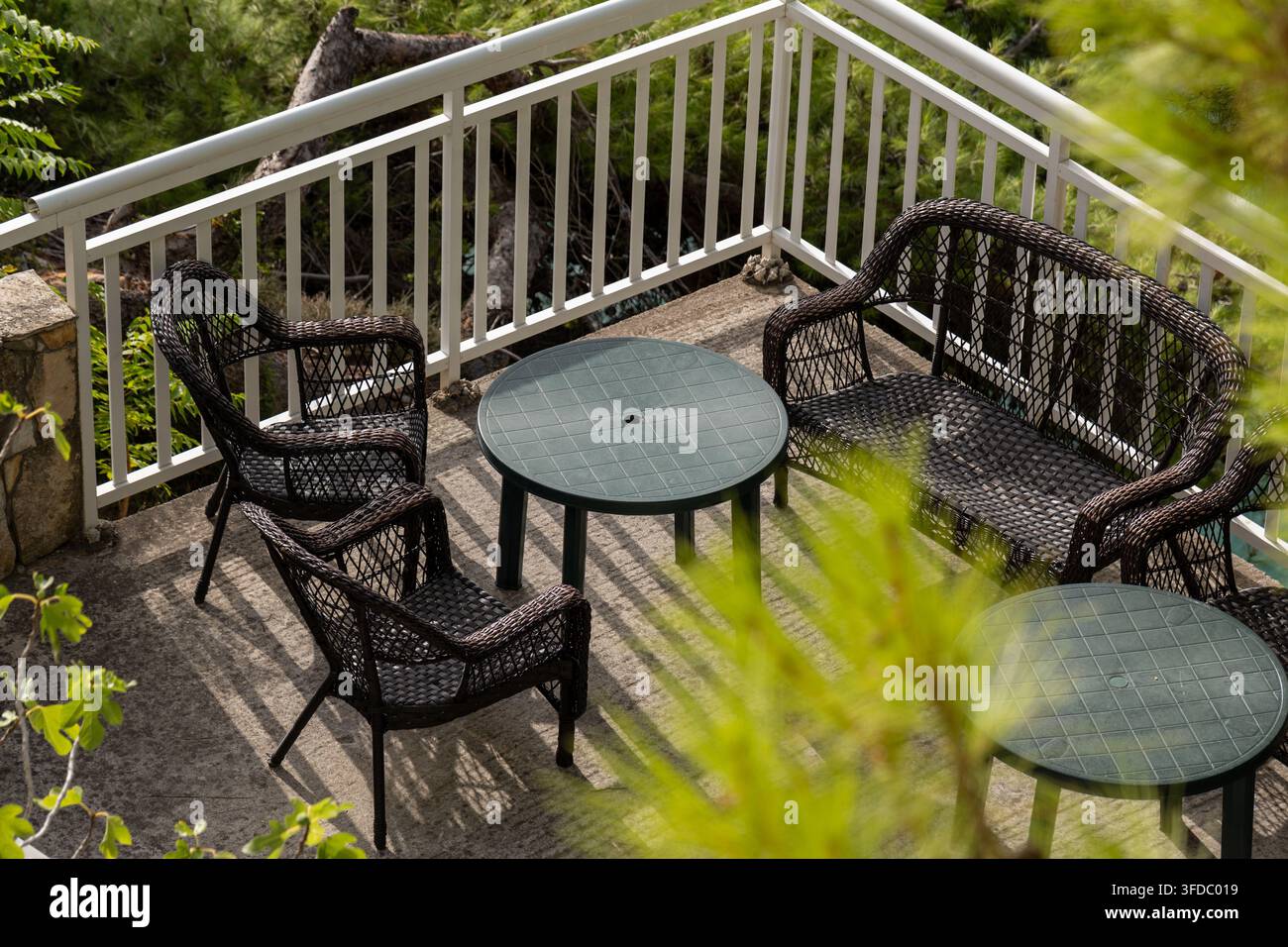 Leere Korb-Patio-Sitzgruppe mit runden Tischen auf sonniger Terrasse Stockfoto