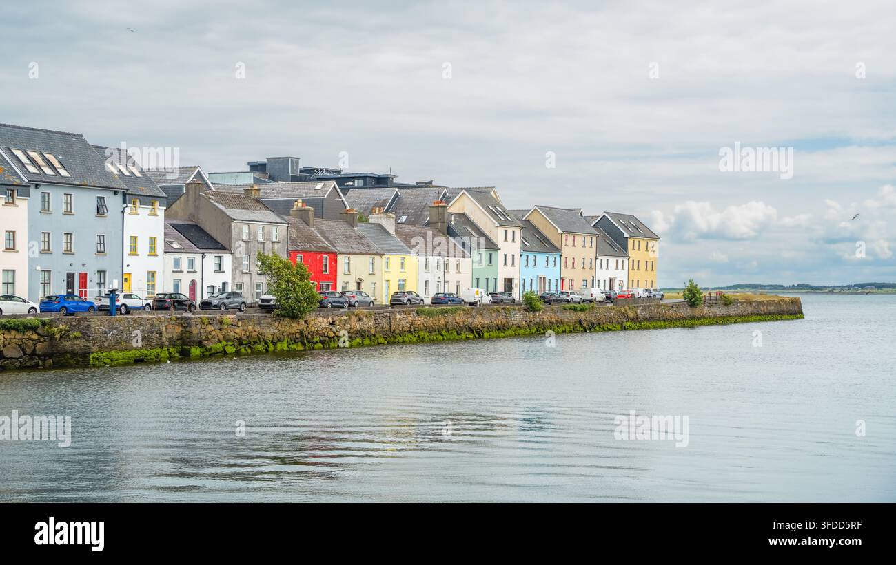 Die ikonische Uferkontinuität zeigt sich in den farbenfrohen Häusern und dem steinernen Kai von The Long Walk neben ruhigem Wasser in Galway, Irland, als Wahrzeichen des Reisens Stockfoto