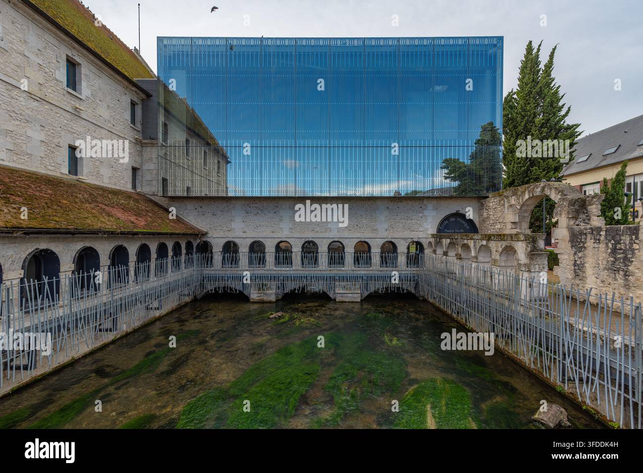 Ein steinernes Kloster mit gewölbten Arkaden und einem flachen Spiegelbecken führt zu einem auffälligen zeitgenössischen Anbau aus blauem Glas der Maurice-Duruflé-Musik Stockfoto