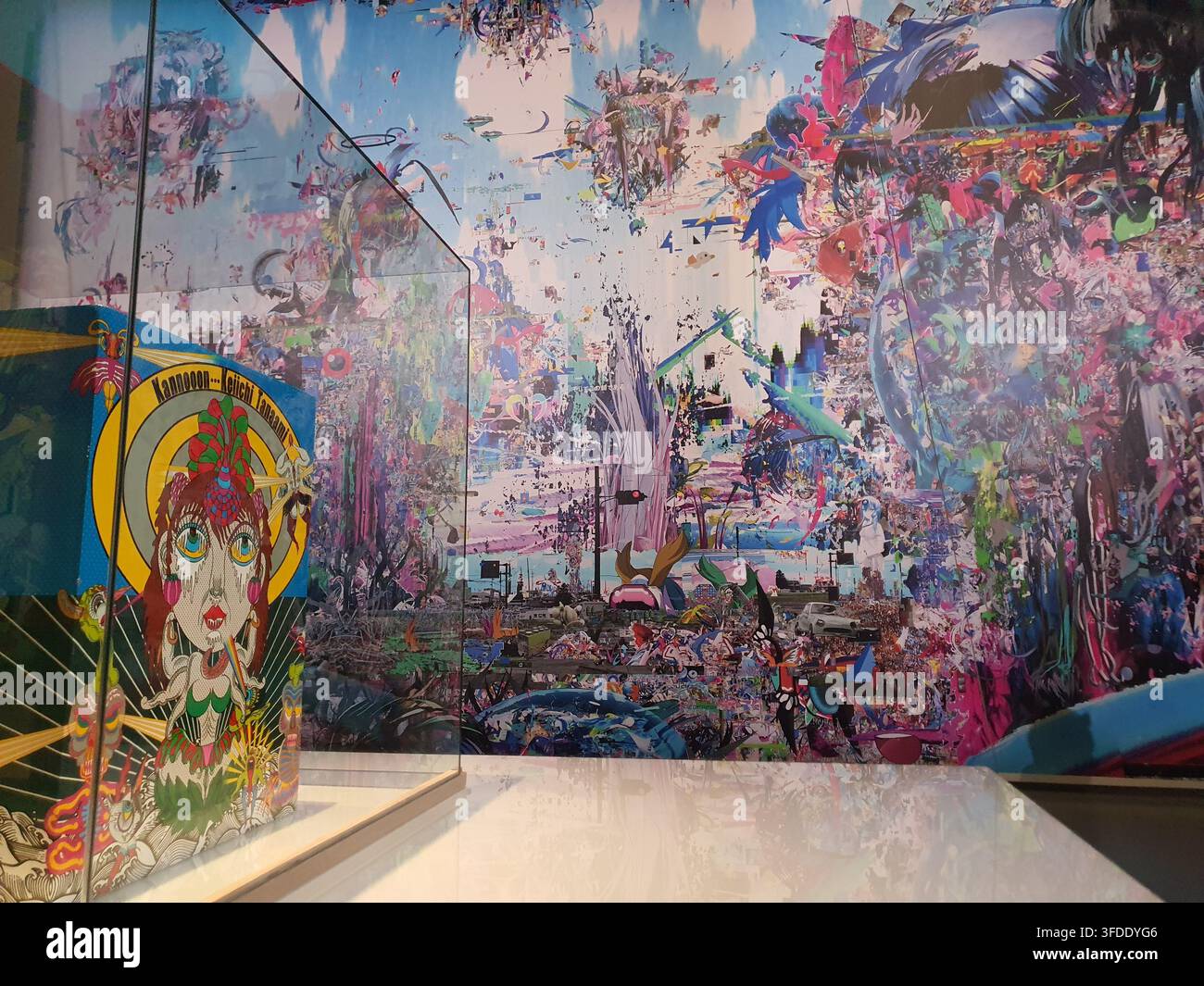 Innenansicht einer zeitgenössischen Kunstgalerie oder eines Museumraums mit einer großflächigen, lebendigen digitalen Wandmalerei, die die gesamte Wand bedeckt. Die Stockfoto