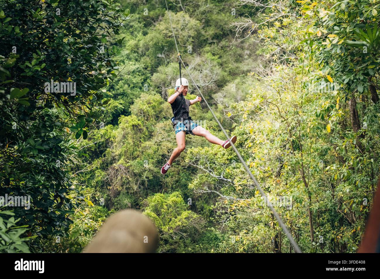 Teenager genießt ein aufregendes Seilrutschen-Abenteuer und fliegt über das dichte Dach des tropischen Regenwaldes auf der malerischen Insel Mauritius während eines aktiven Sommerurlaubs Stockfoto