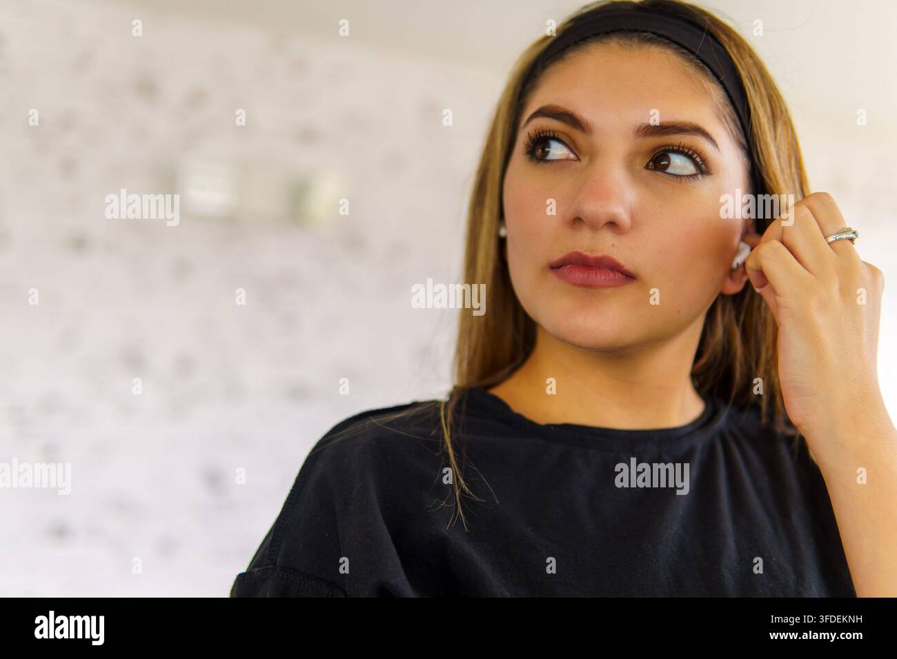 Junge Frau, die nachdenkt, während sie Musik mit kabellosen Ohrhörern hört Stockfoto