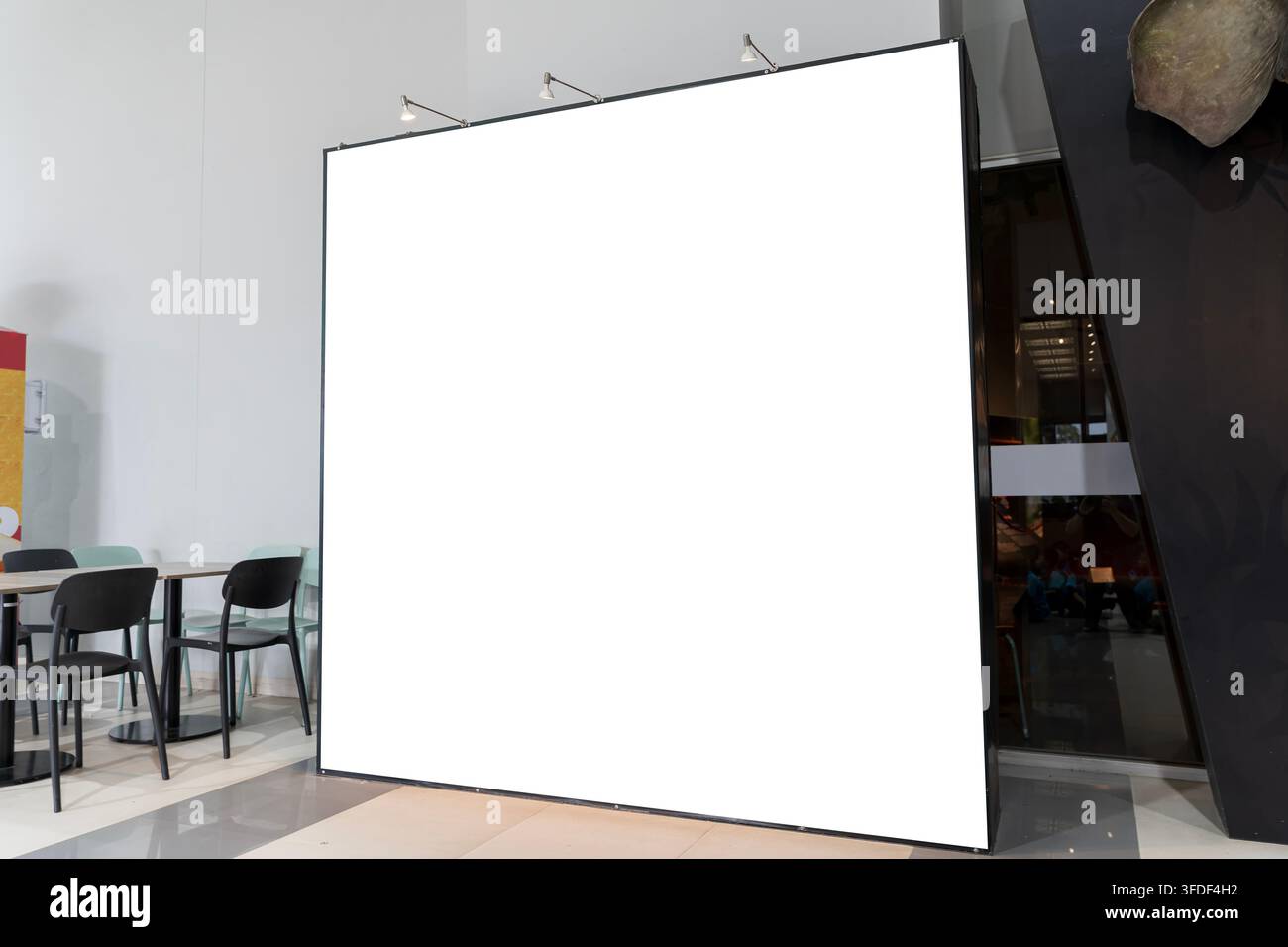 Übergroßes leeres Werbeschild mit Deckenstrahlern in einem zeitgenössischen Innenraum, bereit für Werbung, Branding, Ausstellungsgrafik, Werbekampagne Stockfoto