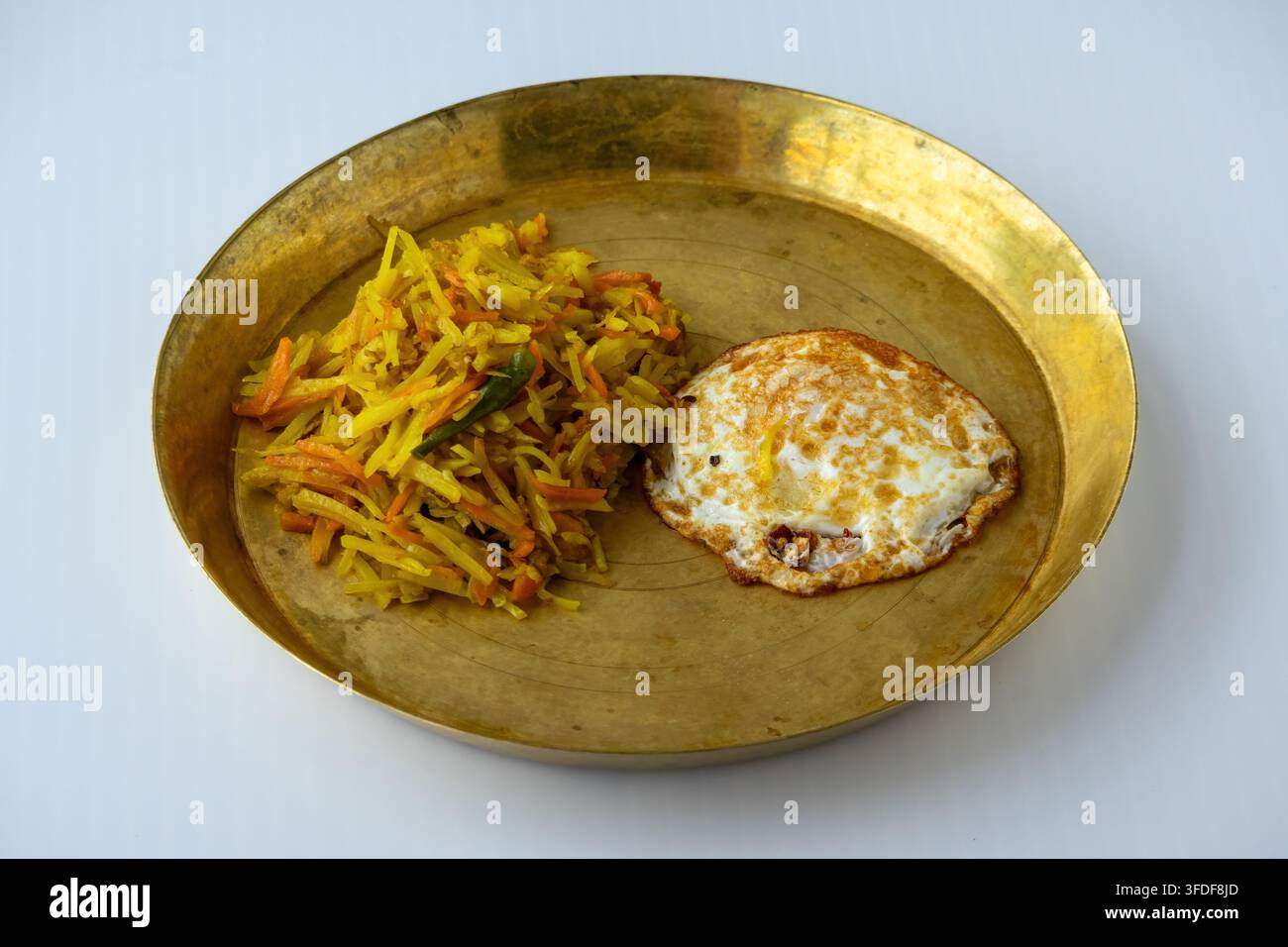 Traditionelles bengalisches Frühstückstablett mit gebratenen Kartoffel- und Karottenstreifen, Bratkartoffeln und gebratenem Ei, serviert auf einem Messingteller. Hausgemachtes südasiatisches mea Stockfoto
