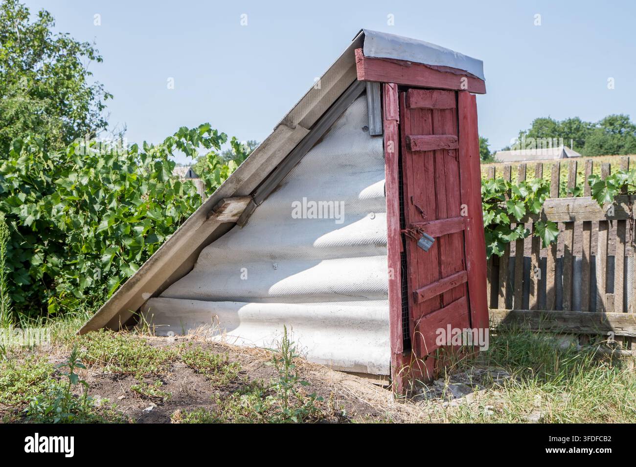 Der Dorfkeller ist ein Graben mit einer Holztür. Keller zur Lagerung landwirtschaftlicher Produkte. Stockfoto