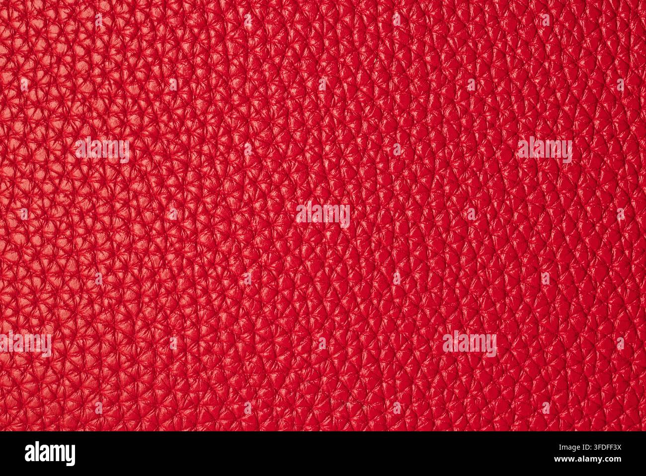 Makro-Hintergrundtextur aus hellrotem, mit Kieselsteinen bedecktem echtem Ledermaterial Stockfoto