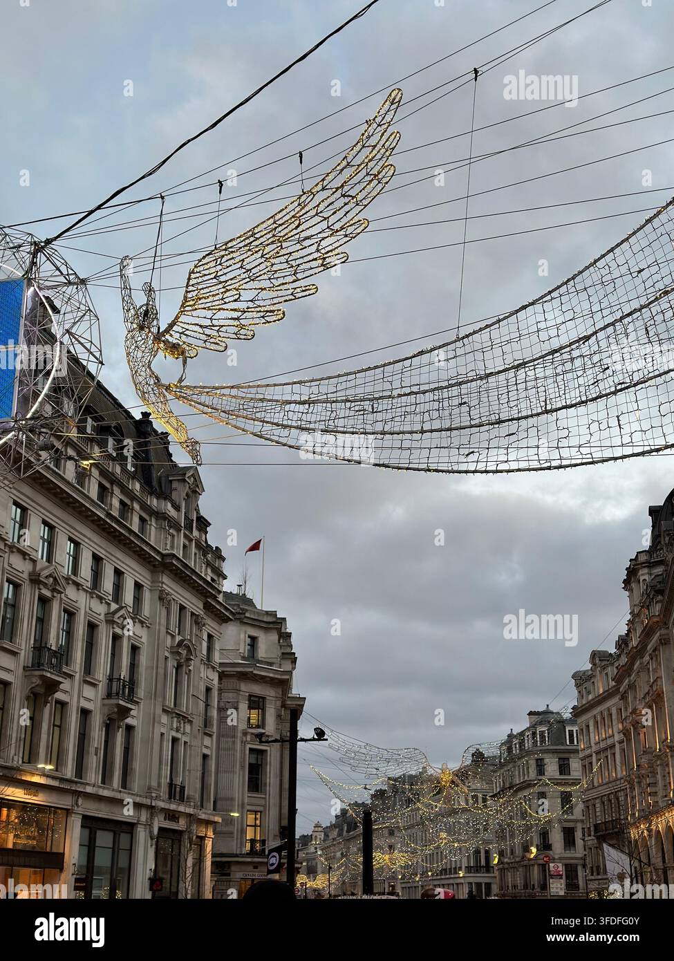 Die Geister von Weihnachten, Engel-Lichtinstallationen, die über den historischen Gebäuden der Regent Street während der Feiertagszeit in London, UK, schwebend sind. - Smartphone-aufgenommenes Stockfoto
