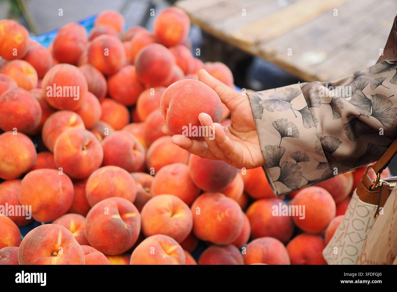 Hält einen Pfirsich auf einem Markt bei warmem Wetter Stockfoto
