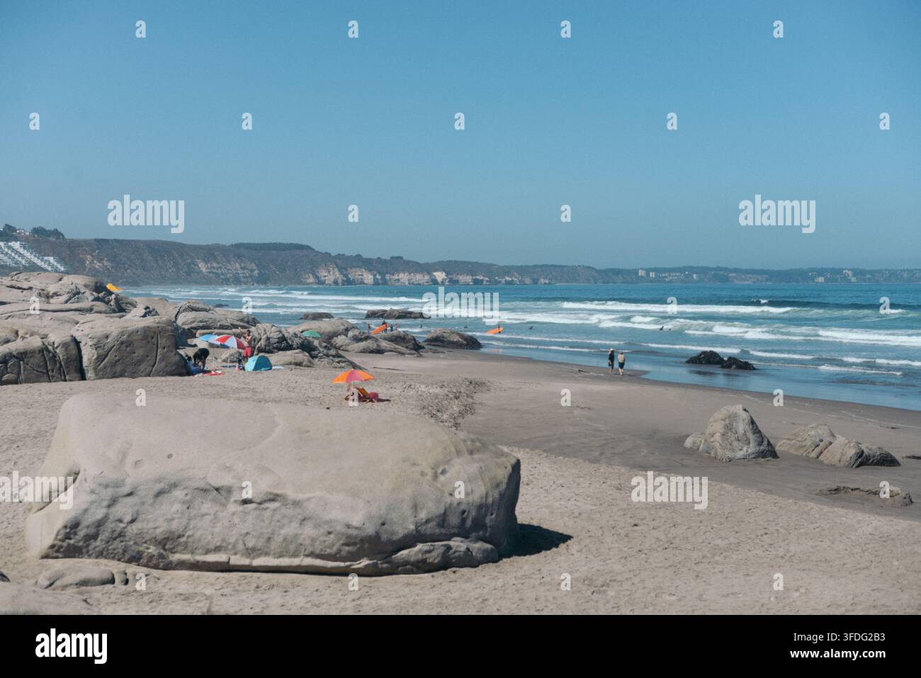 Menschen, die an einem sonnigen Tag an einem felsigen Strand entspannen Stockfoto