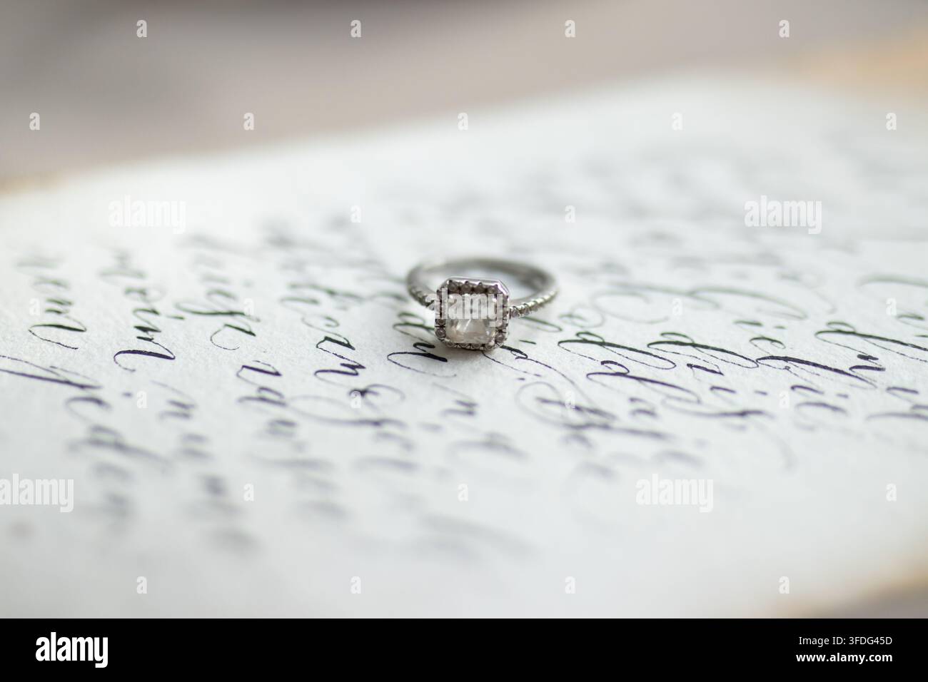 Eleganter Diamantring, der auf einem handgeschriebenen Liebesbrief ruht Stockfoto