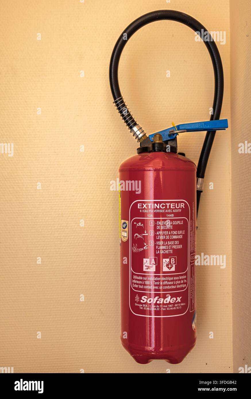 Dijon Frankreich 23. August 2026. Roter Sofadex-Feuerlöscher mit Anweisungen auf einer schlichten Innenwand im Gebäude montiert. Sicherheit und Schutz Stockfoto
