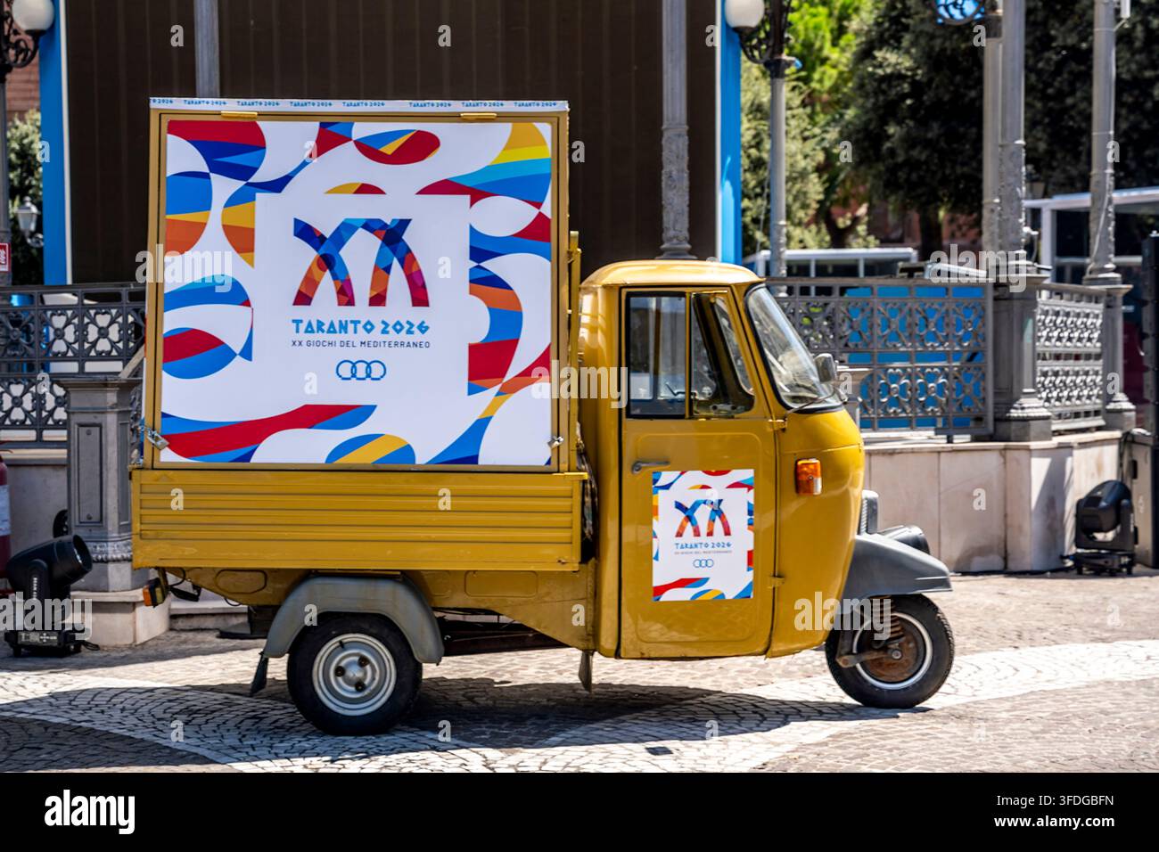 Ape-Auto zeigt das Logo der 20. Mittelmeerspiele Taranto 2026 auf der Piazza Garibaldi, Veranstaltungsförderung im Stadtzentrum, Taranto, Italien Stockfoto