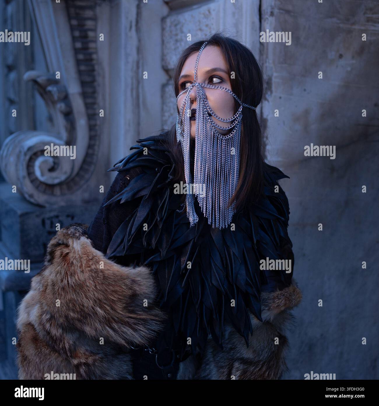 Fantasy-Kriegerfigur in einem Ketten Schleier und schwarzer Feder-Rüstung, Cosplay-Kostüm-Porträt in der Nähe alter Steinmauern. Quadratisches Format für soziale Medien. Stockfoto