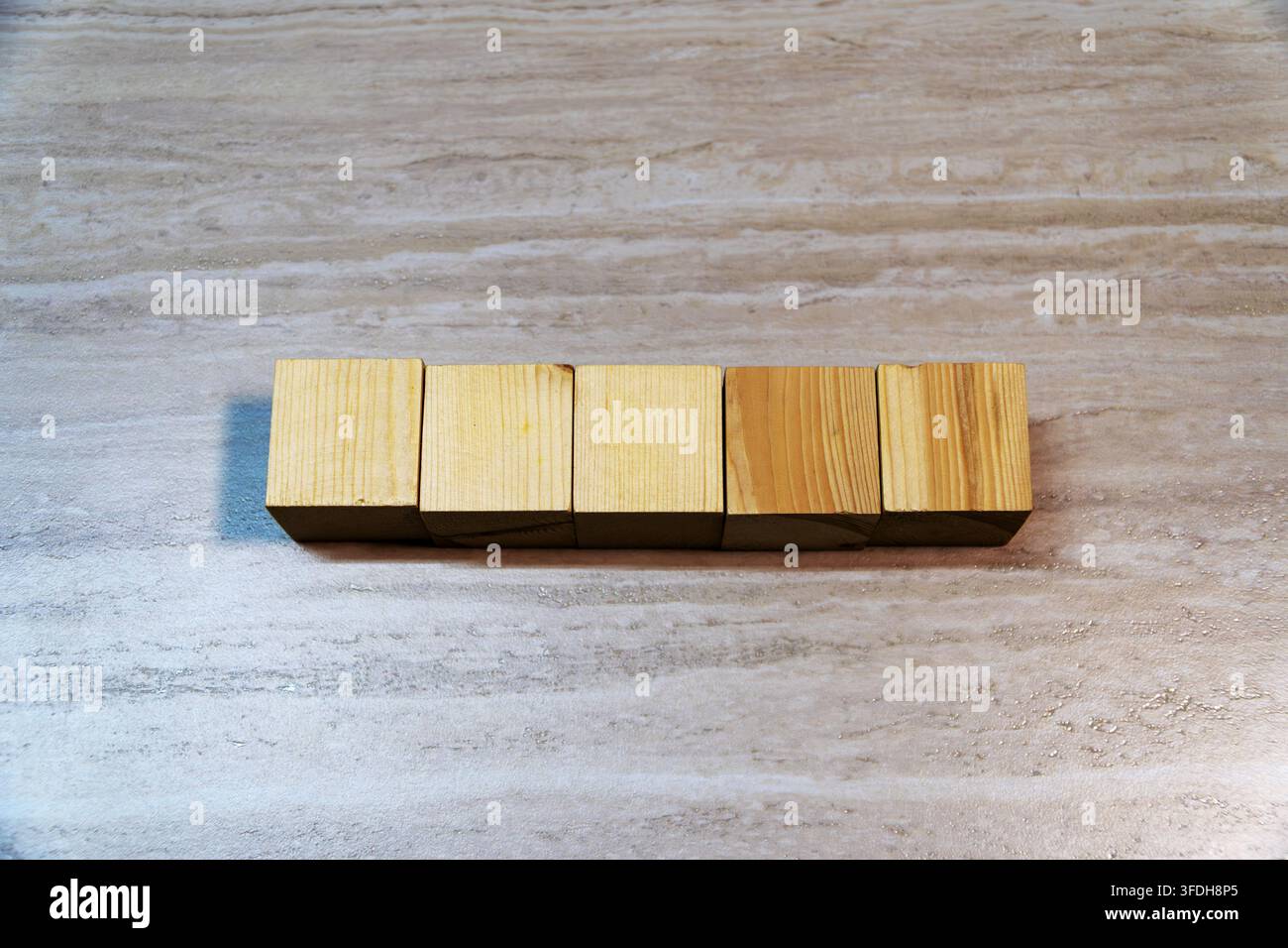 Oberansicht von fünf leeren Holzwürfeln, die auf einem hellen Holzuntergrund aufgereiht sind. Kopierraum für Text, Wort, Datum oder Modell. Stockfoto