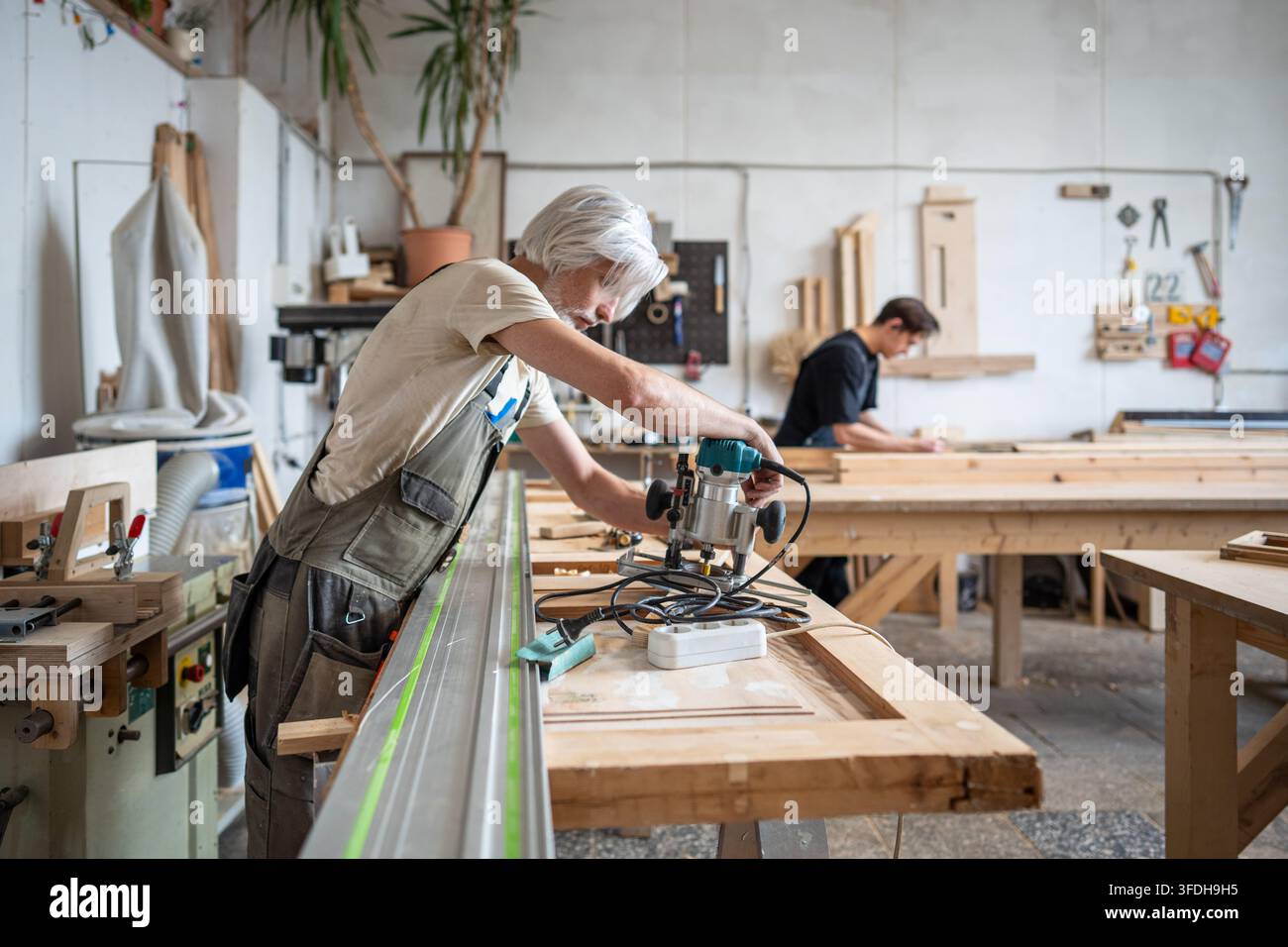 Holzarbeiteringenieur bereitet eine elektrische Holzfräsmaschine am Arbeitsplatz in einer Restaurierungswerkstatt vor. Stockfoto
